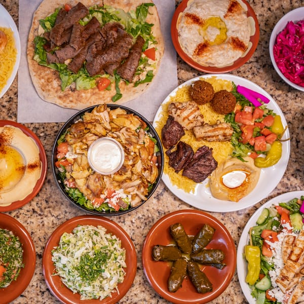A table full of Joe's Falafel dishes, including falafel, hummus, shawarma, and salads.