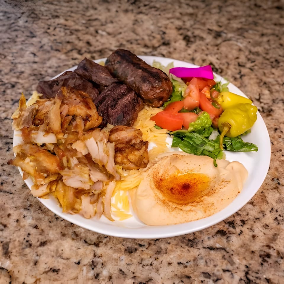 A Joe's Falafel plate with shawarma, kebab, hummus, salad, and pickled vegetables.