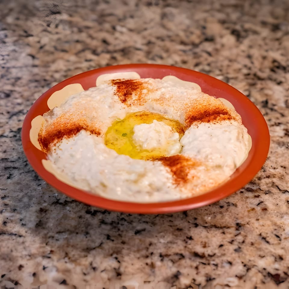 Joe's Falafel baba ghanoush, topped with olive oil and paprika, in a red bowl.