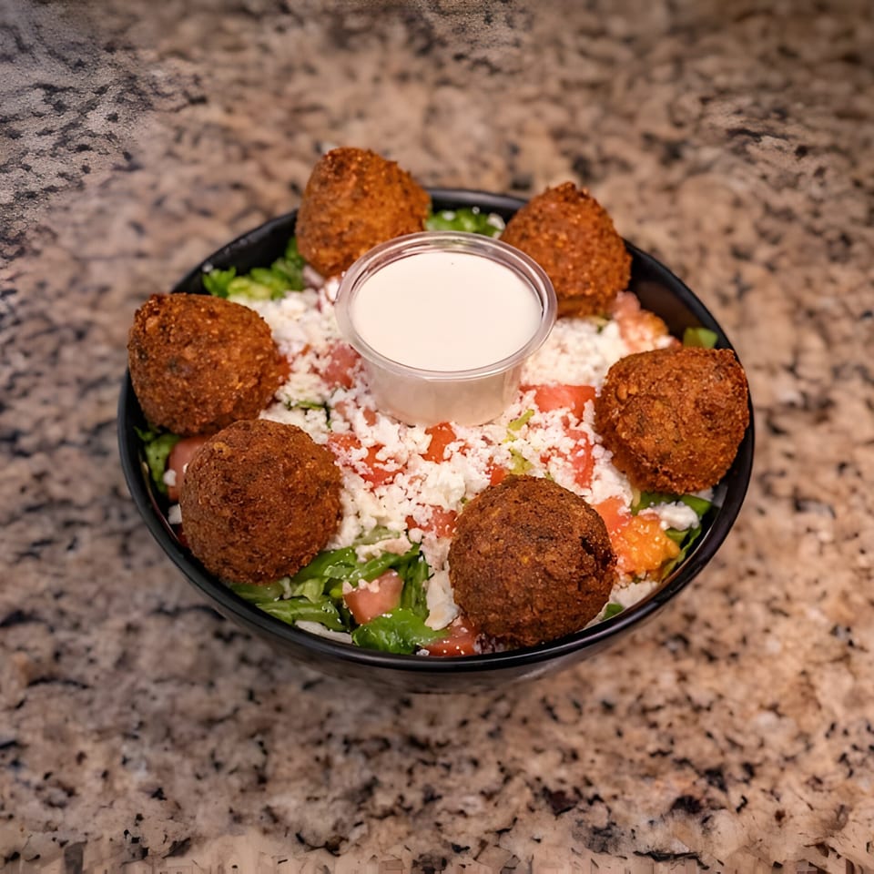 Joe's Falafel salad with six falafel balls, crumbled feta, tomatoes, and dressing.