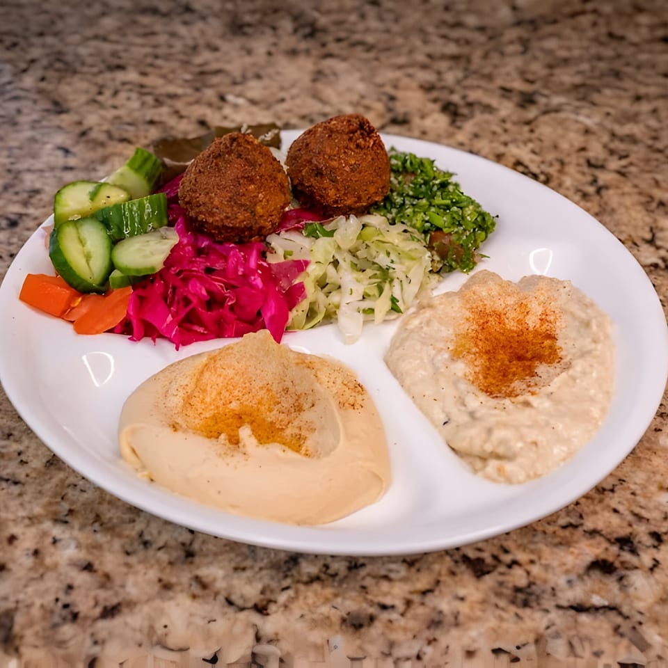 Joe's Falafel plate with falafel, hummus, baba ghanoush, tabbouleh, pickled cabbage, and vegetables.